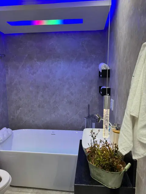 Banheiro com banheira e iluminação azul no forro de gesso