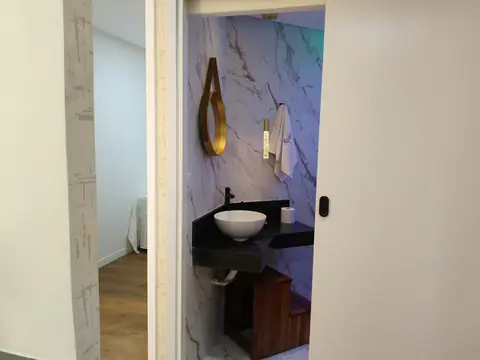 Lavabo com parede de mármore, cuba de apoio e bancada escura