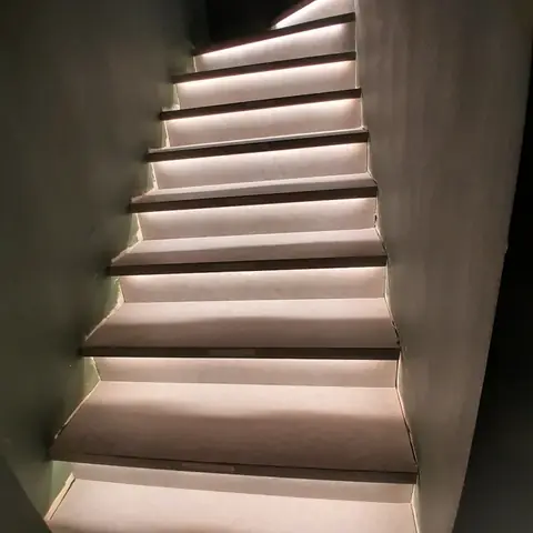 Escada com fita de LED embaixo de cada degrau, iluminando a subida