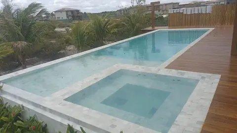 Piscina de borda com prainha, cercada de deck de madeira